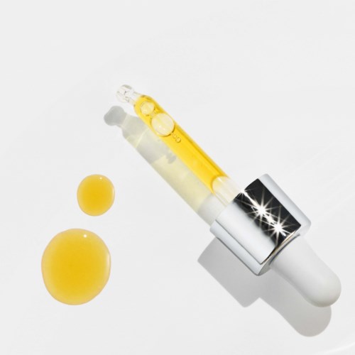 Eine Pipette mit gelber Flüssigkeit, zwei gelbe Pillen und ein weißer Hintergrund.