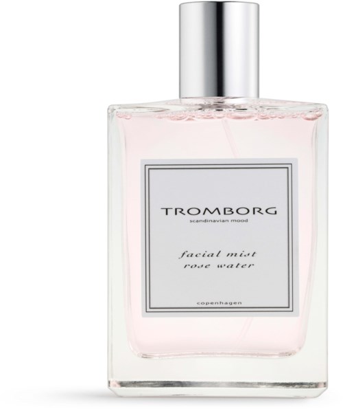 Eine klare Parfümflasche mit silberner Kappe, enthält hellrosa Flüssigkeit, beschriftet 'Tromborg facial mist rose water'.