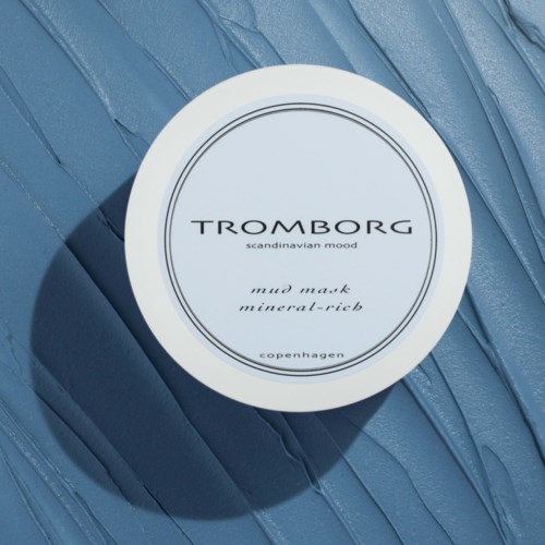 Ein weißer runder Behälter auf einer strukturierten blauen Oberfläche. Das Etikett liest 'Tromborg Scandinavian Mood Mud Mask'.