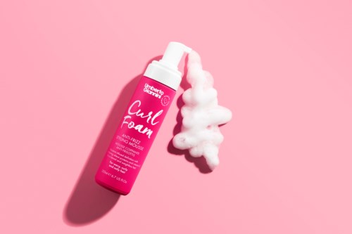 A pink bottle labeled 'Cush Foam' with foam spilling out on a pink background.