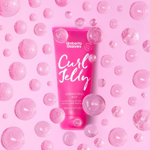 En rosa tub märkt 'Curl Jelly' omgiven av flytande bubblor på en rosa bakgrund.