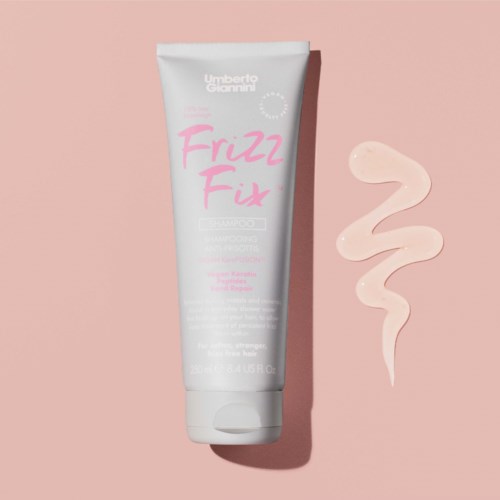Weiße Tube mit Haarpflegeprodukt, rosa und graue Schrift, auf rosa Hintergrund mit cremefarbener Spirale.