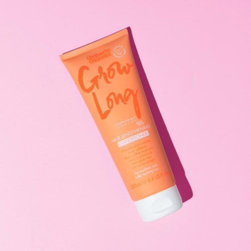 Orangene Tube Haarspülung auf rosa Hintergrund, beschriftet "Grow Long" und "Hair Lengthening Conditioner".