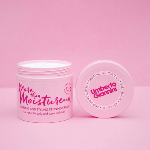 Ein rosa-weißer Behälter mit Haarcreme, Text auf Deckel und Körper, vor rosa Hintergrund.
