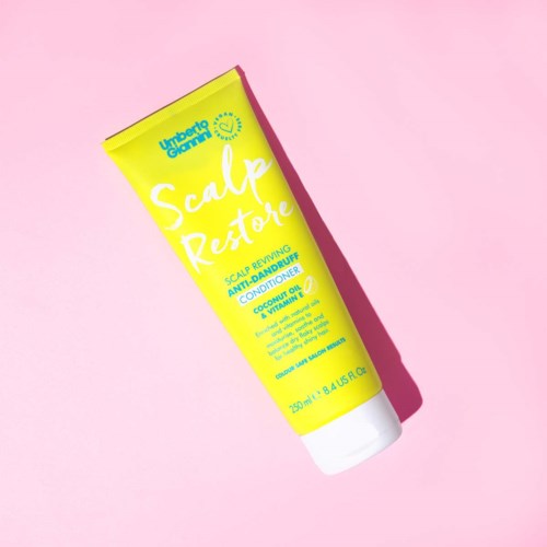 Hellgelbe Tube mit Kopfhautbehandlung, mit Blau und Weißem Text, auf rosa Hintergrund.
