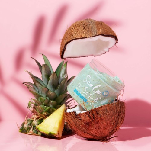 Eine Kokosnuss und Ananas mit Eiscreme darin, auf rosa Hintergrund, schaffen eine tropische Dessertszene.