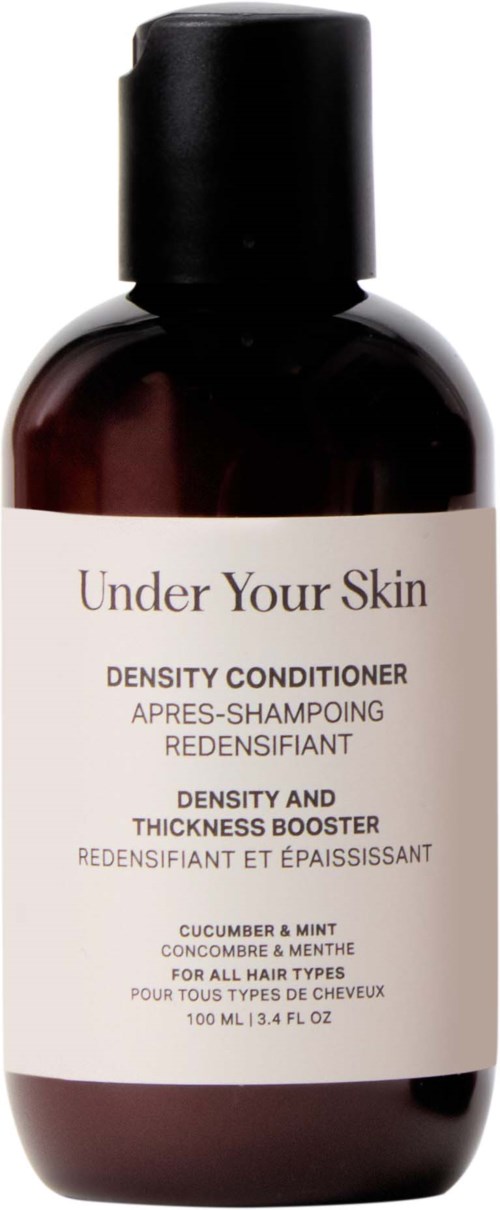 Een donkerbruine fles met wit label voor haarconditioner genaamd 'Under Your Skin' met komkommer en munt geur.