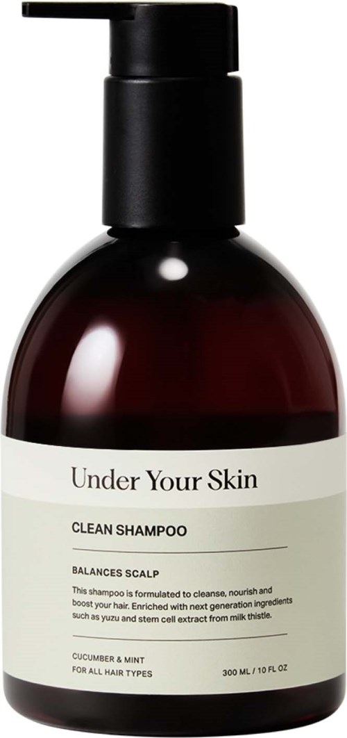Een donker flesje van Under Your Skin schoonshampoo met pomp, label vermeldt hoofdhuidbalans, komkommer en munt.