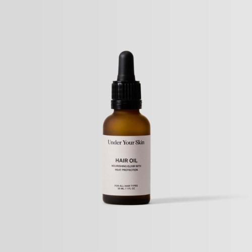 Kleine bruine glazen fles met zwarte druppelkop, gelabeld 'Hair Oil' voor haarvoeding. Simpel ontwerp.