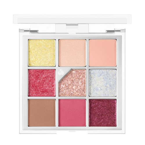 Een make-up palet met negen kleurrijke tinten, inclusief matte, shimmer en glitterafwerkingen, in een wit doosje.