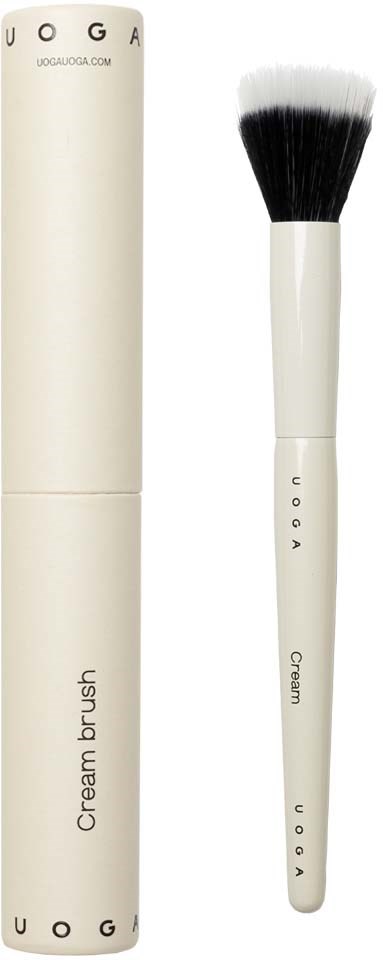Ein weißes Make-up-Pinsel mit schwarzen Spitzen neben einem weißen Behälter mit der Aufschrift 'Cream brush' und 'UOGA.'