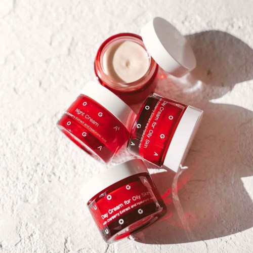 Three small jars of skin cream with white lids, labeled for oily skin, on a textured surface.