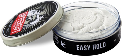 A round open container of hair styling product with a black and white label and a lid nearby.