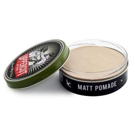 A round container of matte pomade with a black and white label, and a green lid next to it.