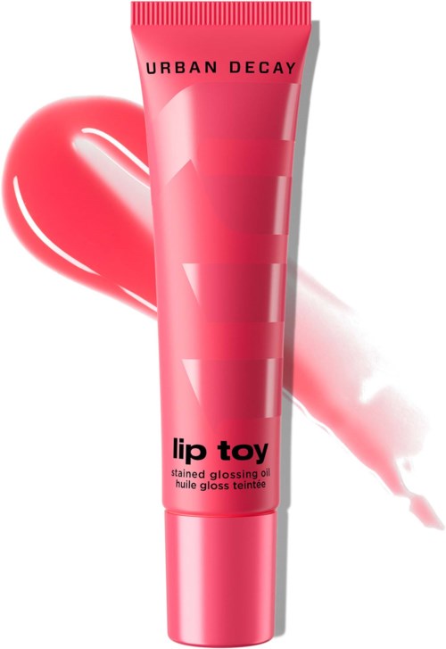 Rosa tub med Urban Decay Lip Toy stänkt gloss med en bakgrund av ett hjärta formad glans och lip gloss streck.