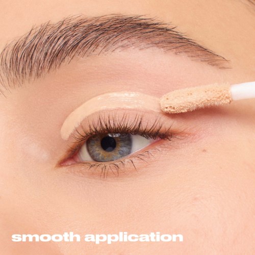 Eine Person trägt Concealer unter dem Auge mit einem Schwammapplikator auf.