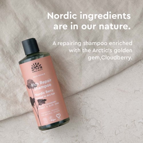 A pink bottle of Rich Repair Shampoo on a beige cloth with text about Nordic ingredients and Arctic berries.