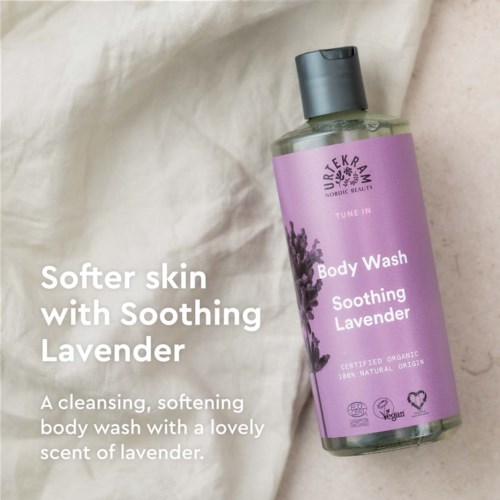 Een lavendel bodywash met kalmerende geur, in doorzichtige fles met paarse label, liggend op crèmekleurige stof.
