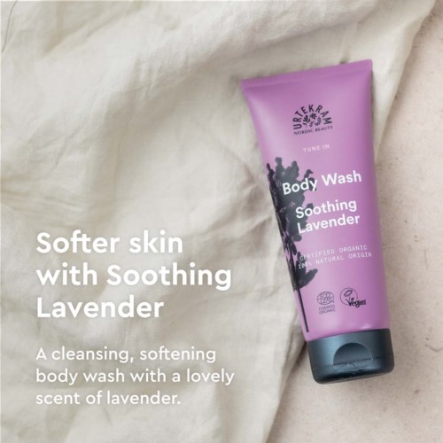 Roze body wash tube met lavendelgeur, geplaatst op lichte stoffen achtergrond.