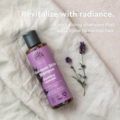 Shampoopullo, jonka etikossa lukee 'Maximum Shine', ja lavendelinkukkia vieressä pehmeällä pinnalla.