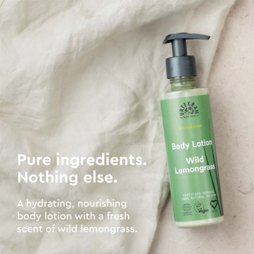 Een groen flesje bodylotion met een zwarte pomp, gemarkeerd 'Wild Lemongrass', op een lichte stof achtergrond.