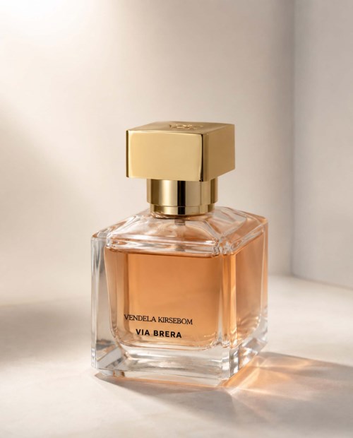 En parfymeflaske i glass med gulllokk, inneholder rosa væske. Tekst på flasken inkluderer Vendela Kirsebom og Via Brera.