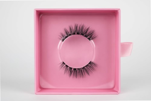 Fake eyelashes inside a pink box with a lid. The box is open, showing the eyelashes neatly placed.