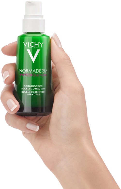 Eine Hand hält eine kleine grüne Vichy V Normaderm Flasche mit Pumpe, Etikett sagt, es ist für Hautpflege und Korrektur.