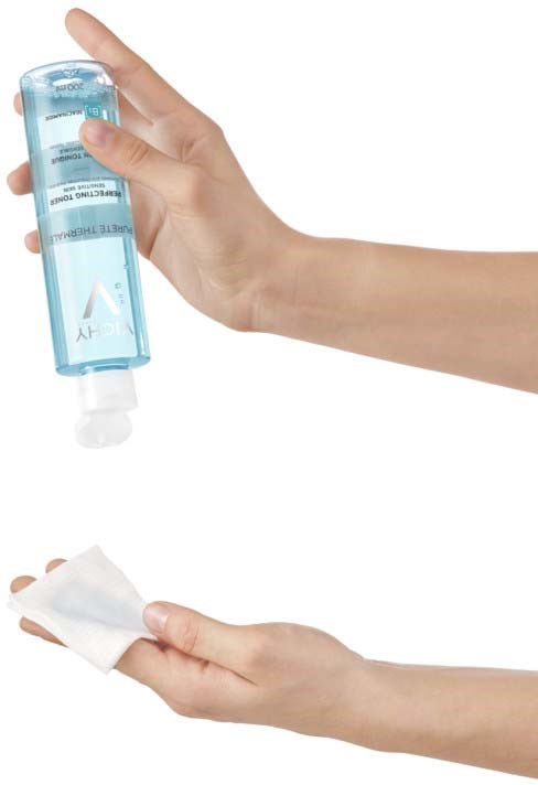 Hände halten eine blaue Flasche Handdesinfektionsmittel und ein weißes Tuch zum Reinigen oder Abwischen.
