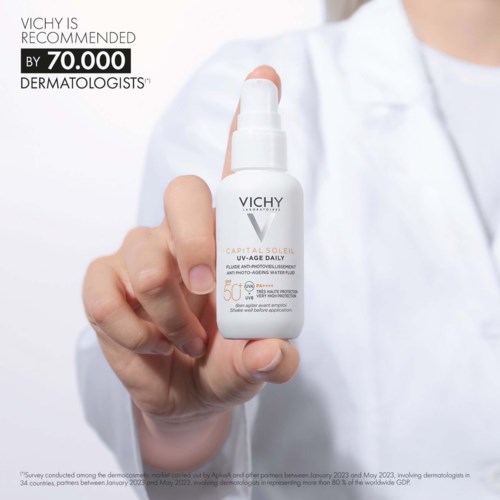 Eine Hand hält eine weiße Vichy Hautpflege-Sprühflasche mit Text über Empfehlungen von Dermatologen und SPF 50.