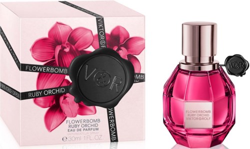Een roze parfumfles met een zilveren dop en een doos met roze bloemen en een zwart zegel.