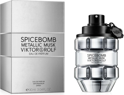 Een parfumfles in de vorm van een handgranaat, met zilveren en zwarte details naast een doos. De doos heeft de naam van het parfum.