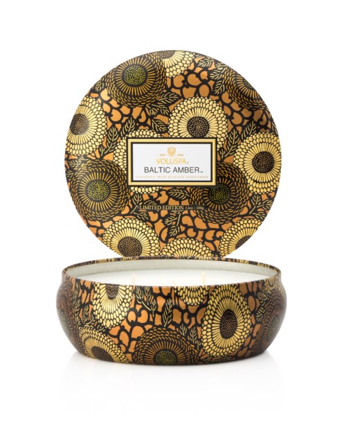Dekorative Kerze mit schwarzen und orangenen Blumenmustern auf Deckel und Basis, etiketti "Baltic Amber."