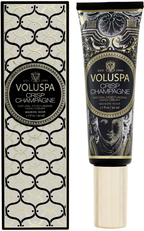 Ein schwarz-gold gemusteter Karton und eine schwarze Tube mit ähnlichem Design, beide sind Kosmetikprodukte mit Bezeichnung 'Voluspa Crisp Champagne.'