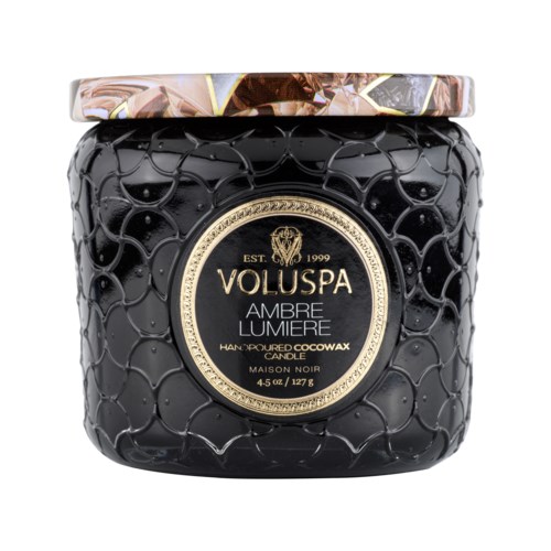 Musta kynttiläpurkki, kultainen etiketti ja koristeellinen kansi, merkintä 'Voluspa Ambre Lumiere' ja valmistettu cocowaxista.