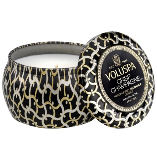 Eine schwarz-goldene dekorative Kerzenverpackung mit Deckel, Beschriftung 'Voluspa Crisp Champagne' und elegantes Design.