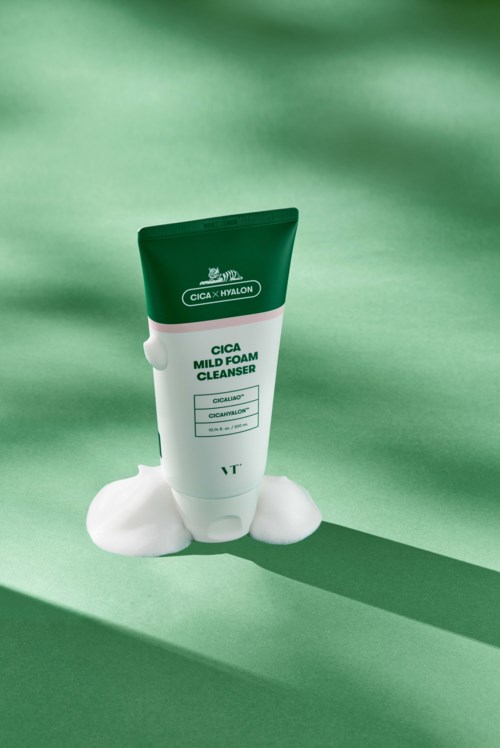 Een tube Cica Mild Foam Cleanser met schuim ernaast, op een groene achtergrond.