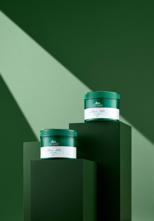 Twee groene cosmetische potten op donkergroene platforms tegen een donkergroene achtergrond met een lichtstraal.