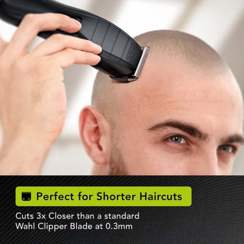 A man with a shaved head cuts his hair using electric clippers. There is a label highlighting benefits for shorter haircuts.