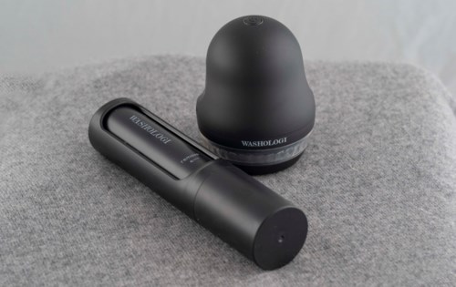 A black toiletry kit and a black portable speaker on a gray surface.