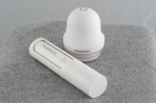 A white electronic device and a white spray bottle are placed on a grey surface.