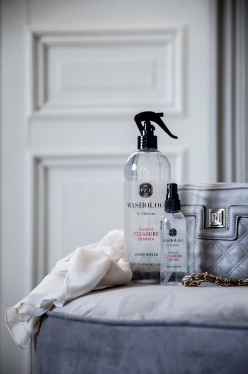 Cleaning spray bottle, small spray bottle, silver purse, and white cloth are on a bed.