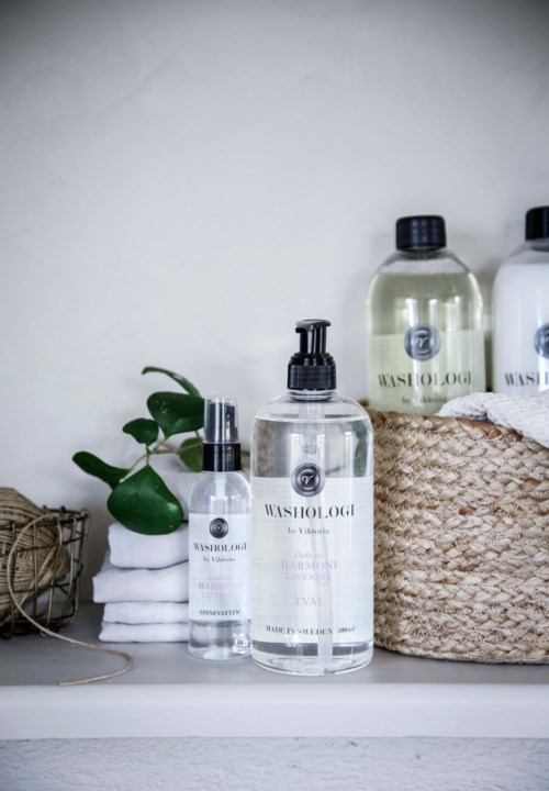 Several bottles of skincare products, a potted plant, towels, and a woven basket on a shelf.