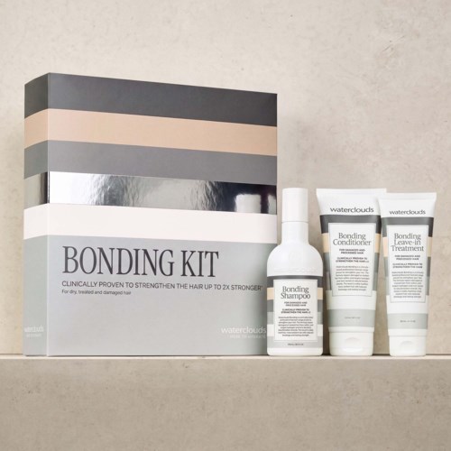 Bonding kit with shampoo, conditioner, and leave-in treatment in white bottles and tubes on a shelf.