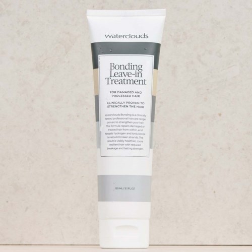 Eine weiße Tube Waterclouds Bonding Leave-in Treatment für beschädigtes, behandeltes Haar, mit schwarzen und weißen Text, auf beigem Hintergrund.