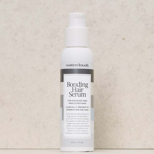 Een witte fles met pomp met label 'Bonding Hair Serum' van Waterclouds staat tegen een eenvoudige achtergrond.