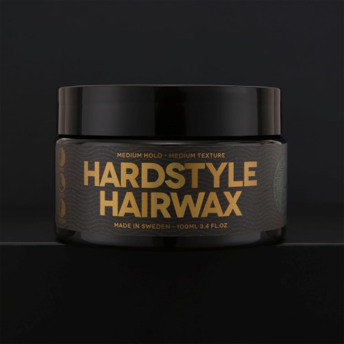 Een zwarte pot met goudkleurige tekst voor hardstyle haarg wax, gemaakt in Zweden, met een zwarte deksel.