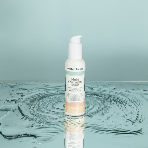 Een witte pompflacon met Moist Overnight Mask staat op water, waardoor ringen ontstaan op een lichtblauwe achtergrond.