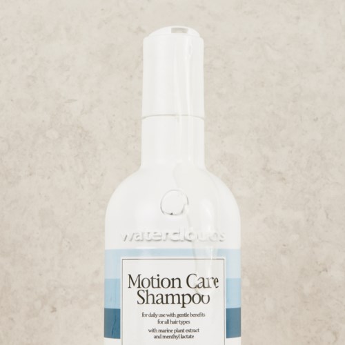 Een witte fles met pomp, gelabeld 'Motion Care Shampoo'. Voor dagelijks gebruik met zeewierextract.