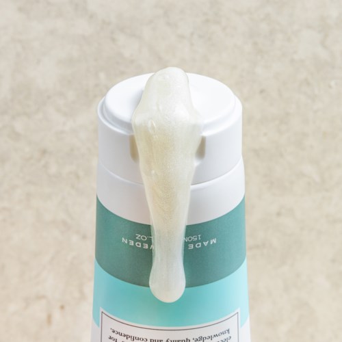 Een witte en groene fles met schuim dat over de rand stroomt.